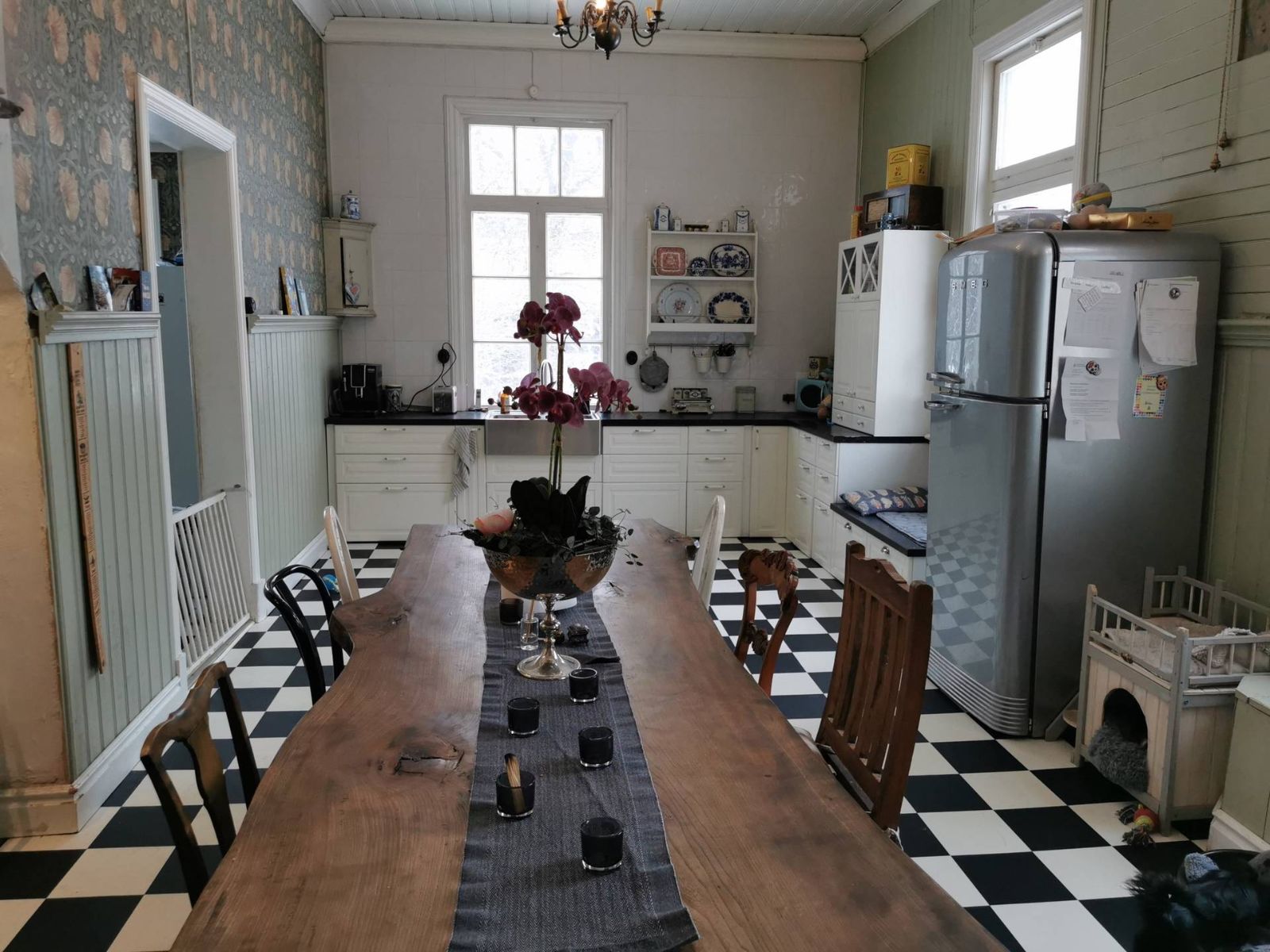 Stort kök med långbord och schackrutigt golv i mangårdsbyggnaden