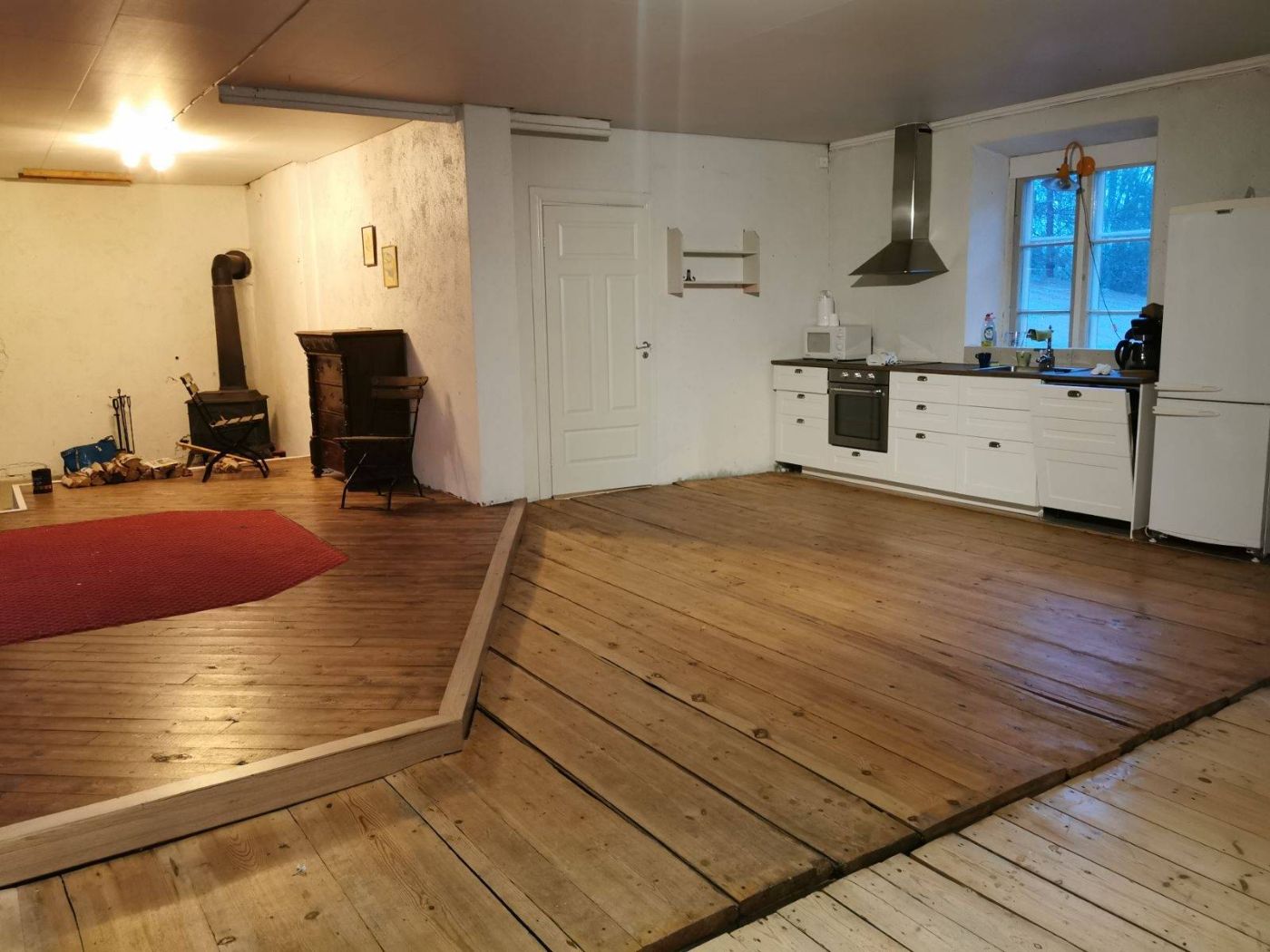 Öppet kök med kamin och breda golvplankor i flygeln