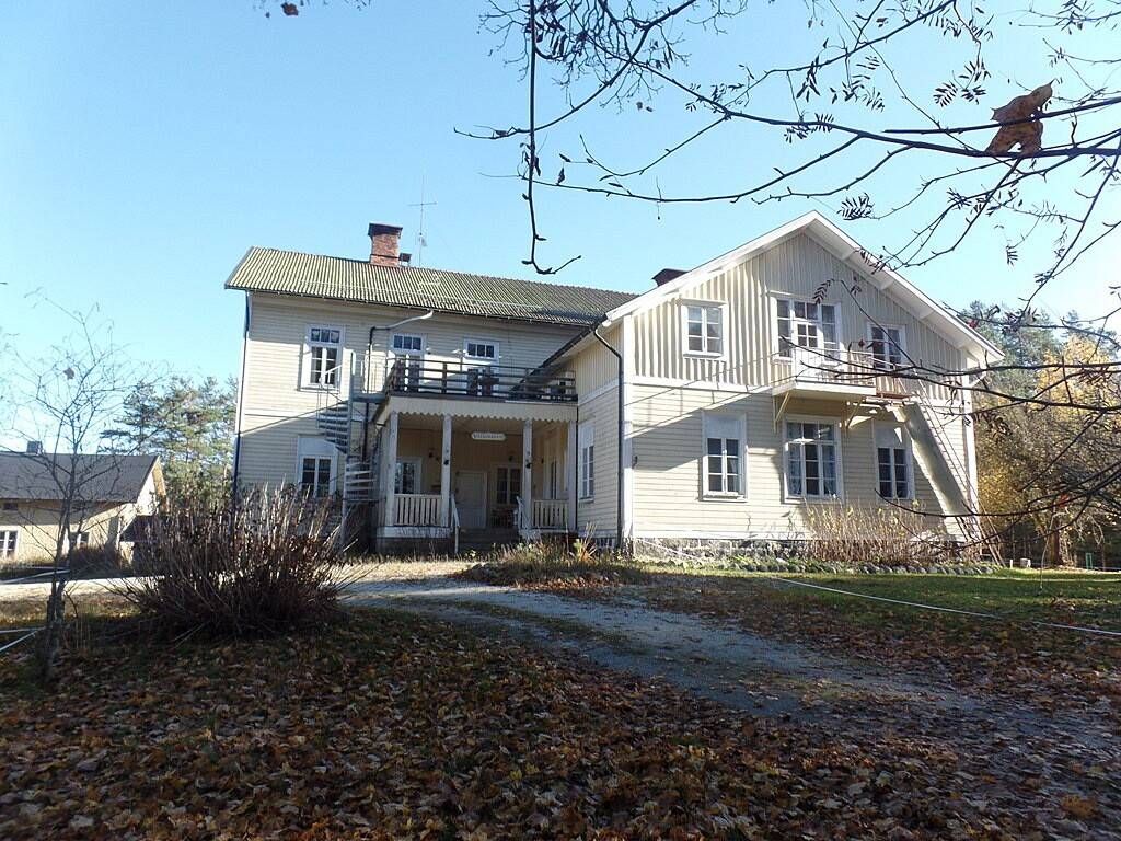 Gul mangårdsbyggnad med veranda och höstlöv på Finnvägen 6 i Ramsberg