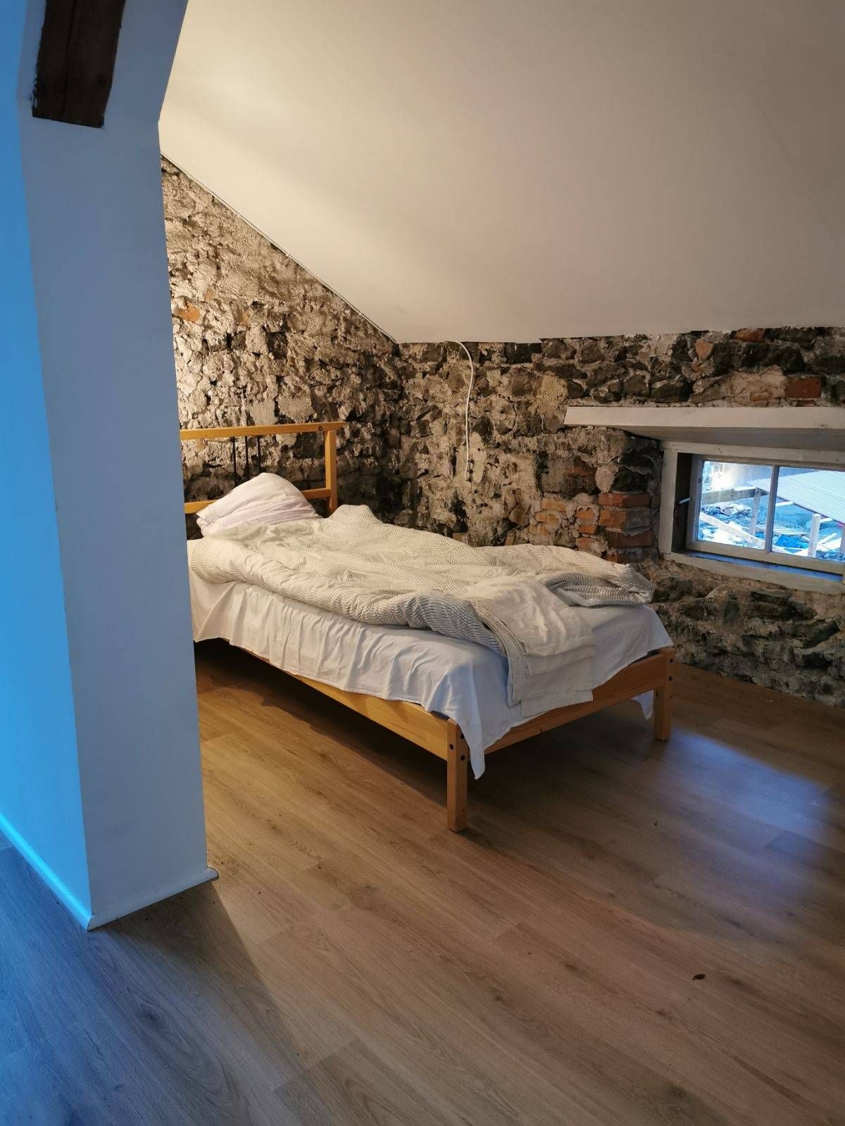 Sovrum under snedtak med frilagd stenvägg