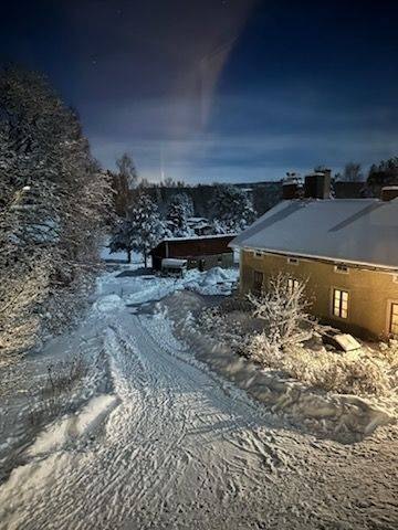 Snötäckt gårdsväg mellan byggnaderna en vinterkväll