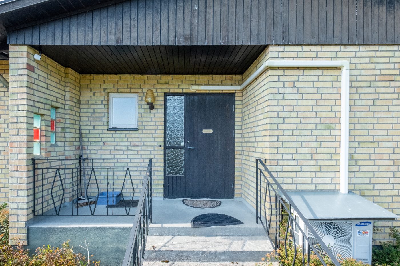 Entré med takad förstukvist och svart ytterdörr