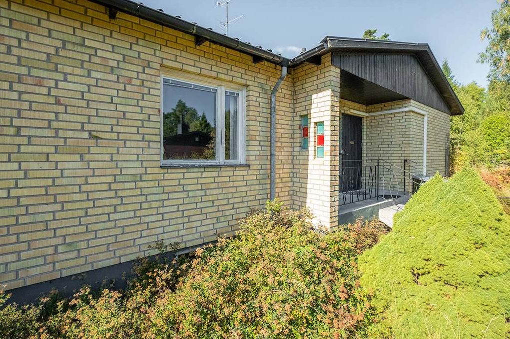 Enplansvilla i gult tegel med entré under skärmtak på Bergsgatan 26 i Valskog